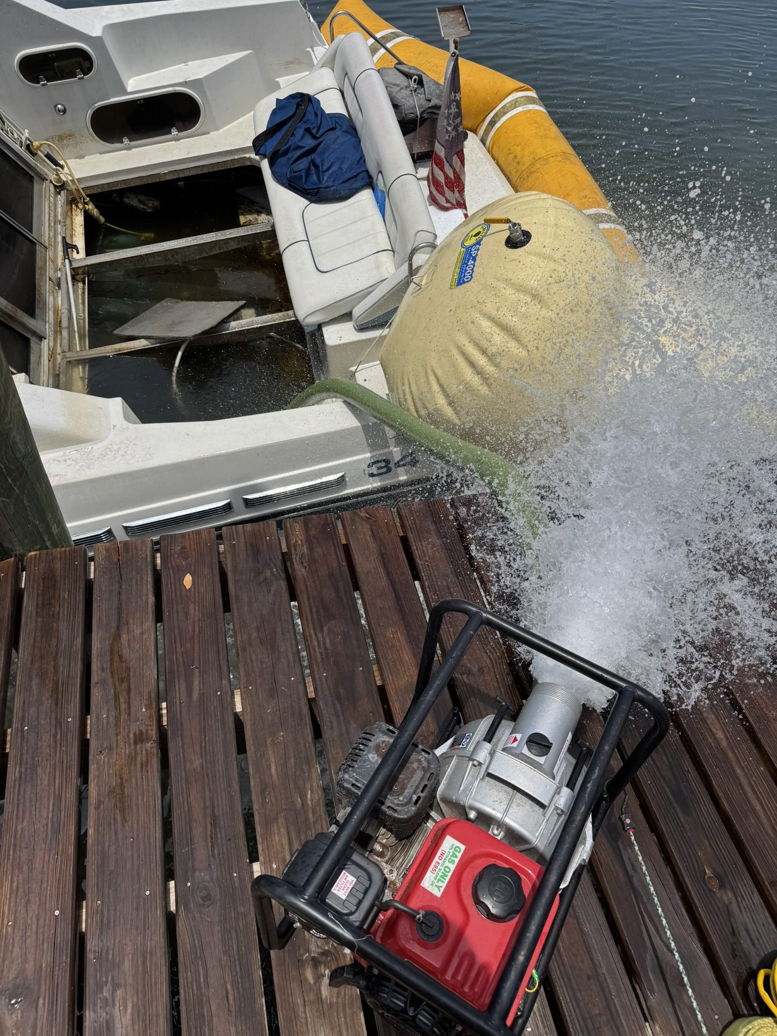 High-volume pump dewatering a partially submerged cabin cruiser at a Southwest Florida dock