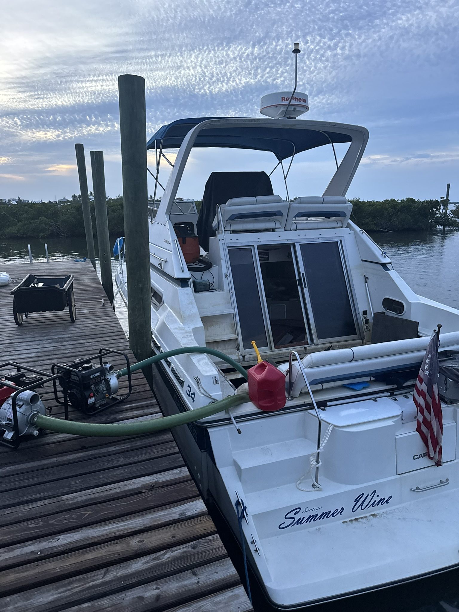 Evening boat recovery monitoring with pumps and hoses at a dock